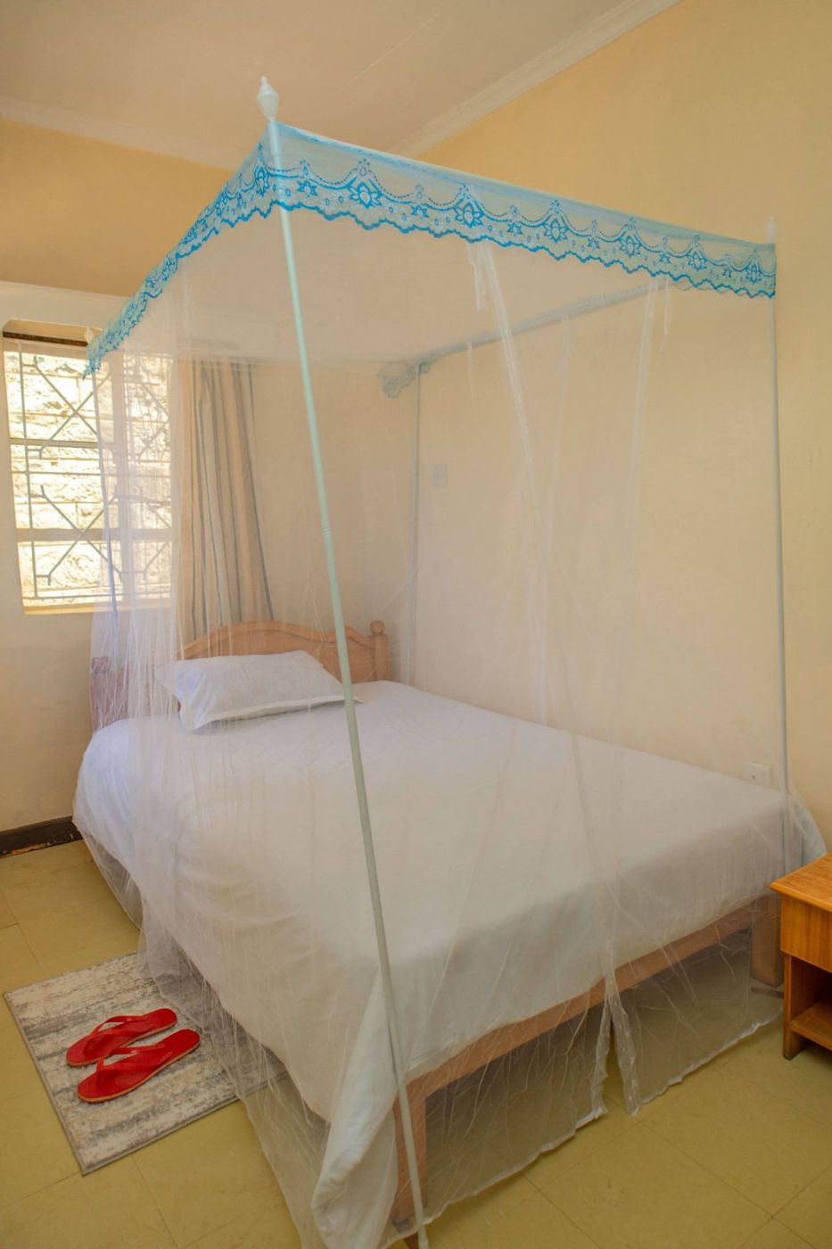 Double room with a mosquito net and red slippers on the rug